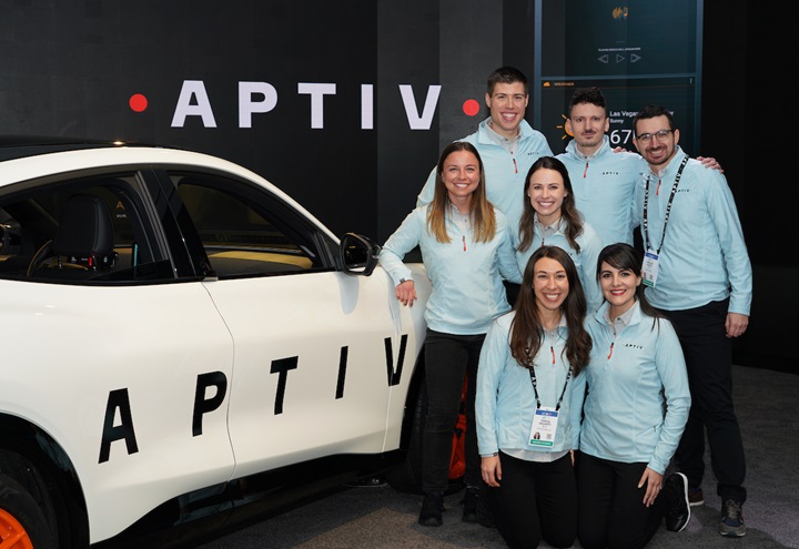 Group of people in blue shirts next to a car