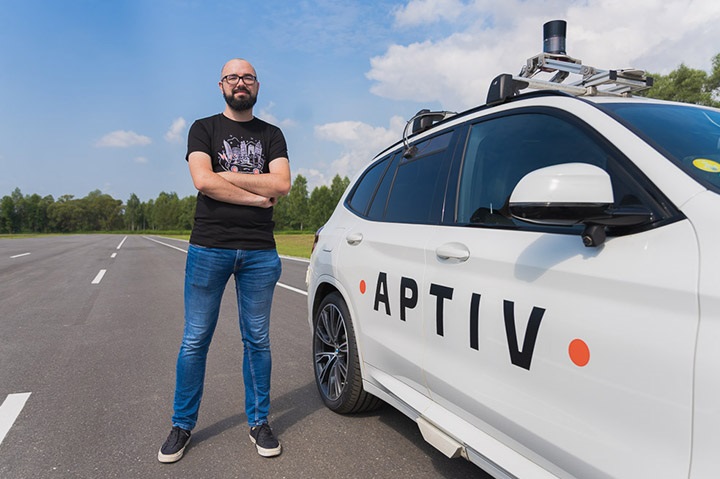Aptiv team side view of car with man standing next to it