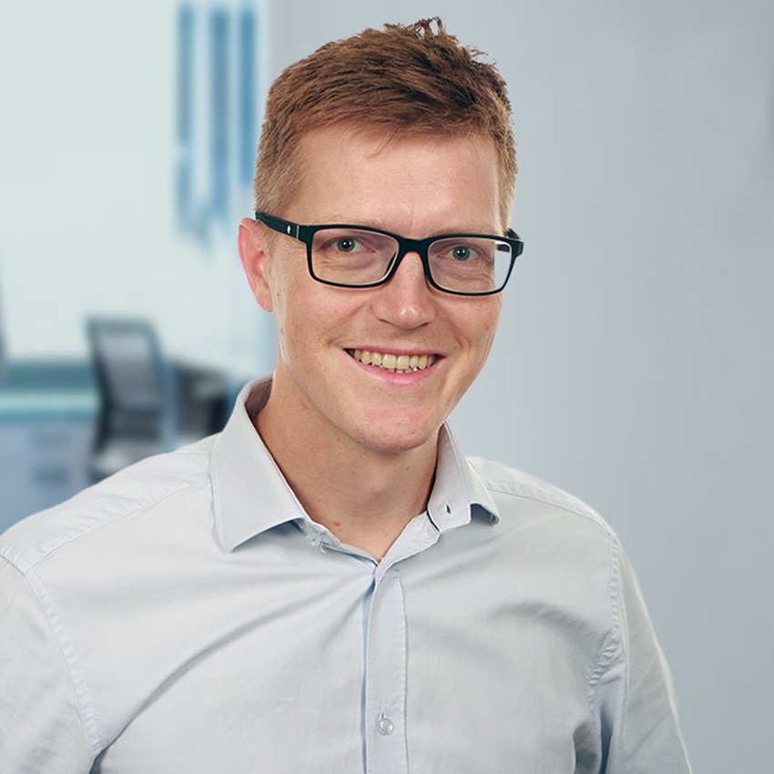 Smiling man with glasses in grey shirt
