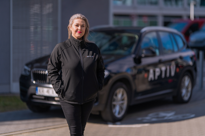 Woman standing in front of car with Aptiv logo